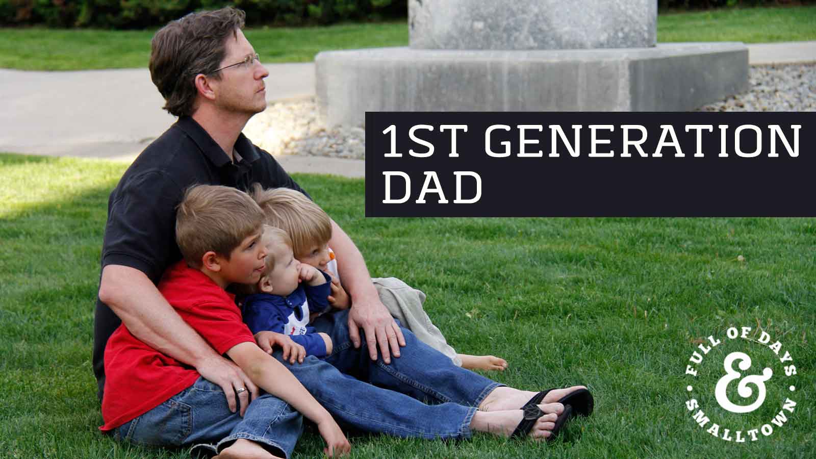 Father and Sons Sitting Together on a Grass Lawn Header