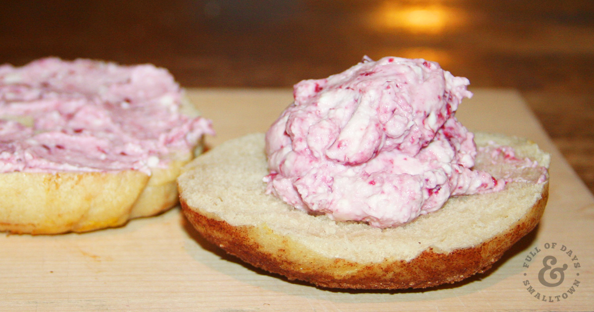 Bagel with raspberry cream cheese on top made from homemade sour cream and cream cheese recipe.