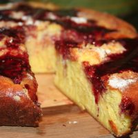 Sourdough Dutch Baby Pancake sliced topped with marionberry syrup and powdered sugar.