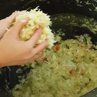 Squeezing and pressing the sauerkraut to release the juices.