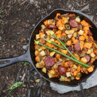 Sweet potato hash in a cast iron skillet on a rocket stove.