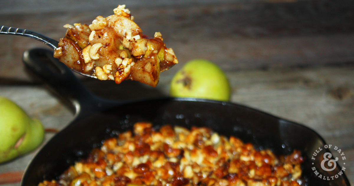 Cashew Walnut Pear Crisp in a Cast Iron Pan with a Spoon Scooping a Steaming Bite