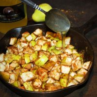 Pears with spices in cast iron pan being drizzled with honey