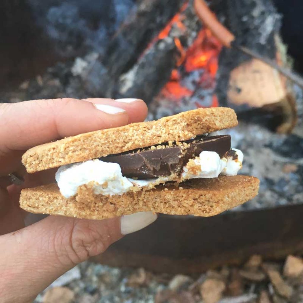 Homemade S'more with a campfire in the background.