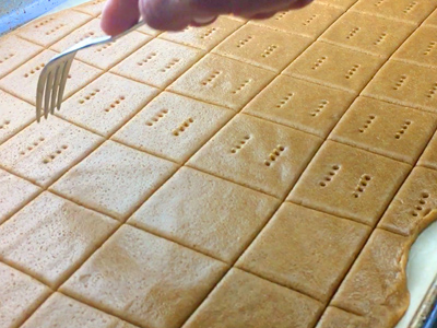 Pricking the homemade graham cracker dough with a fork.