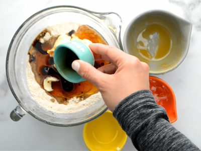 Pouring in the vanilla into the mixing bowl of ingredients for these homemade graham crackers.