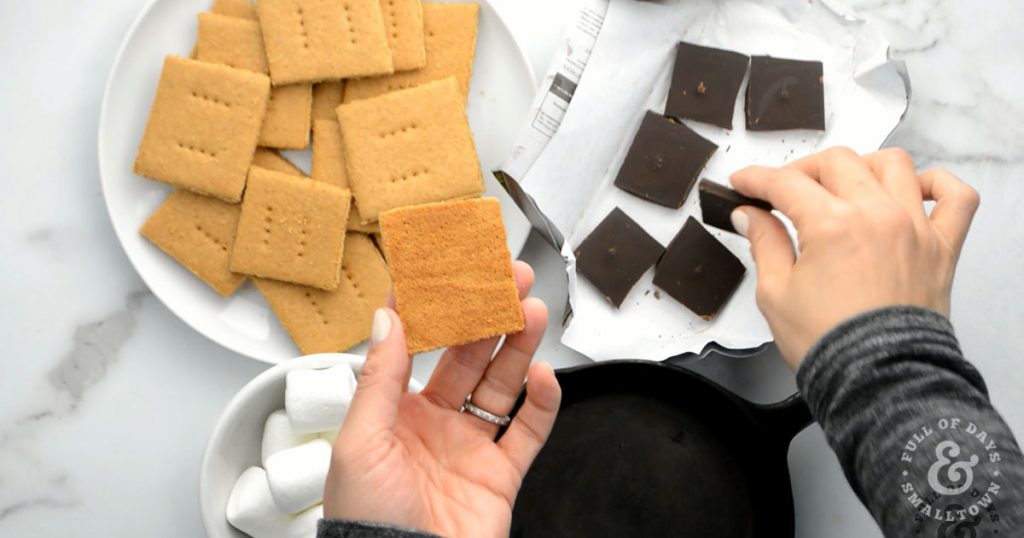 Homemade Graham Crackers, chocolate squares and marshmallows being put together for the perfect s'more.