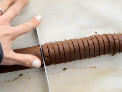 Slicing the chilled log of chocolate cookie dough into rounds for healthy homemade oreos.