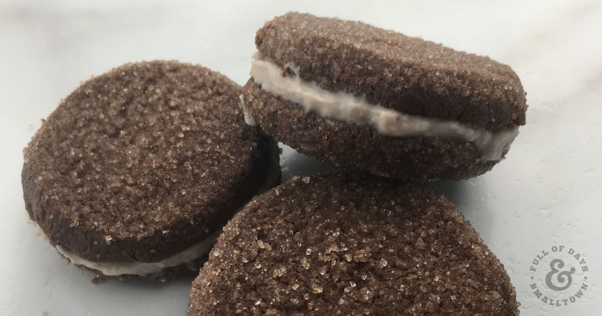 Three homemade Oreo chocolate sandwich cookies stacked on a white countertop.